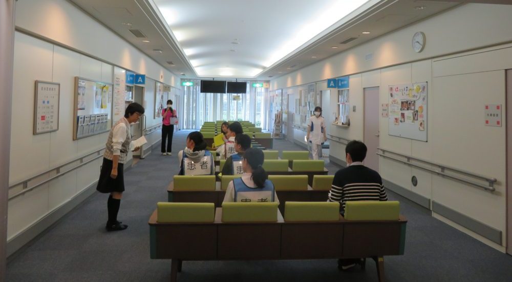 外来の待合で診察を待っていた患者さんに、診療が中止されたことを職員が説明しています。